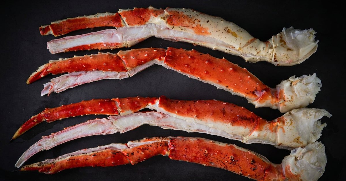 Patas de cangrejo real rojo cocidas y abiertas sobre una superficie oscura